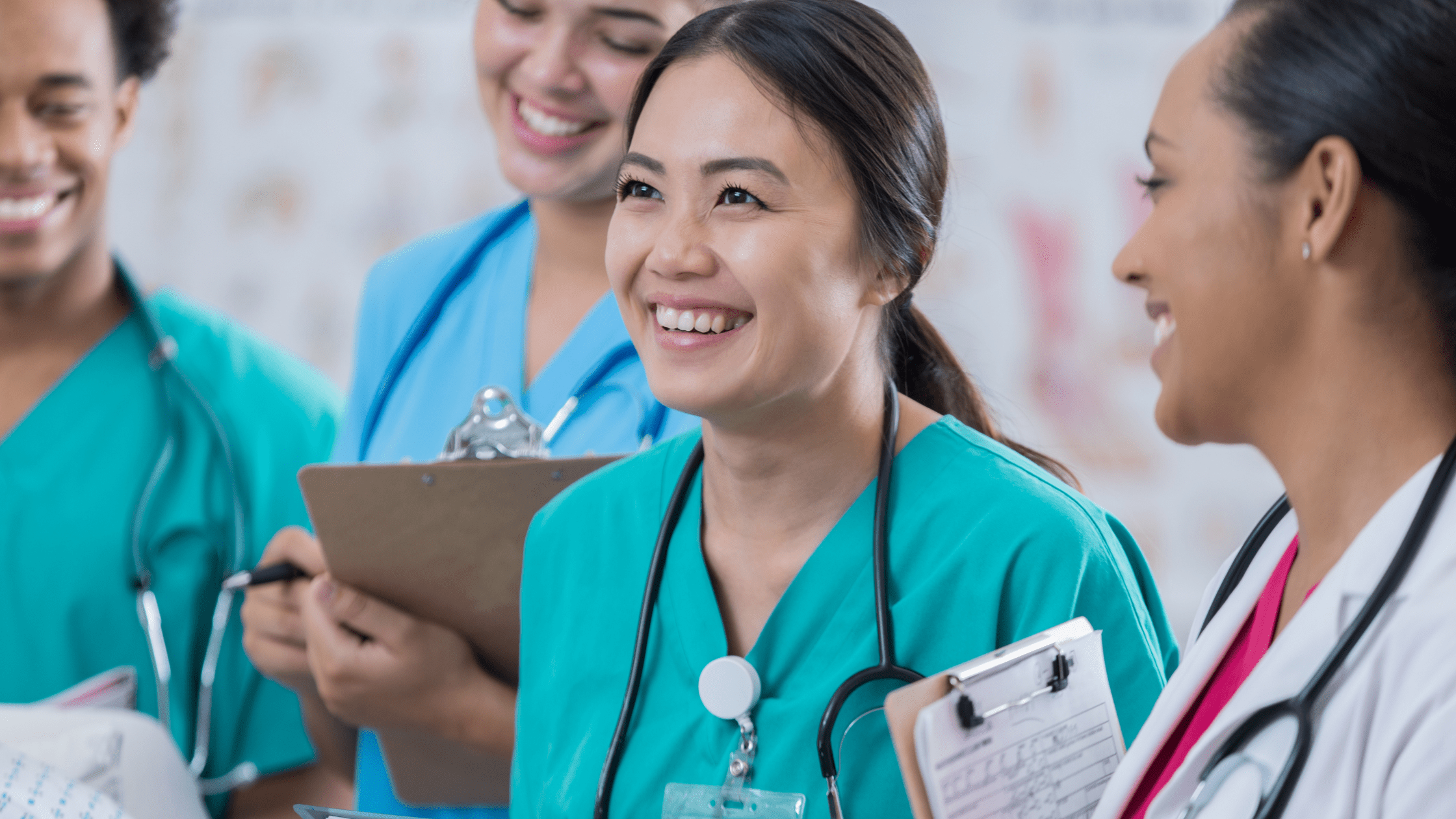 A group of medical residents in a hospital, wearing scrubs and smiling.